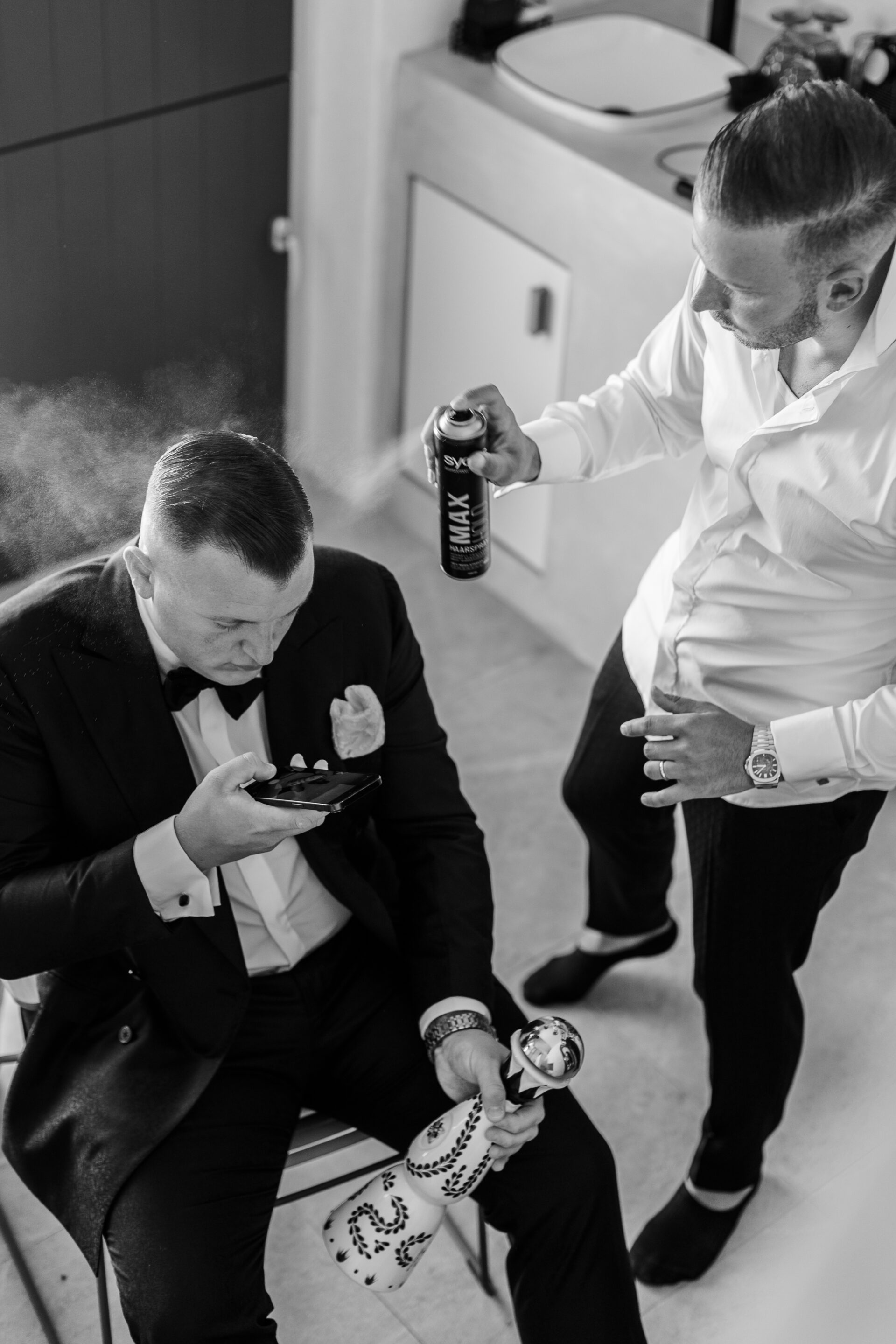 Candid groom getting ready moment in Santorini, styled with hair spray, captured by Santorini photographer