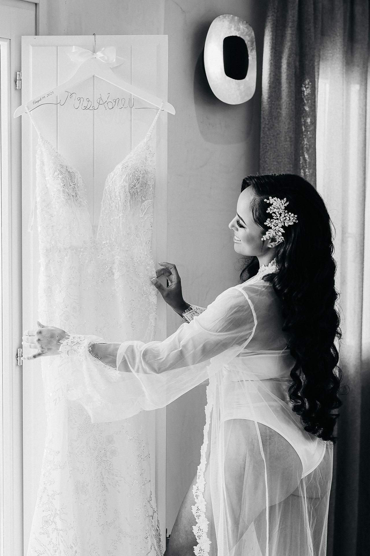 Santorini wedding photographer captures smiling bride holding her lace wedding dress during bridal prep