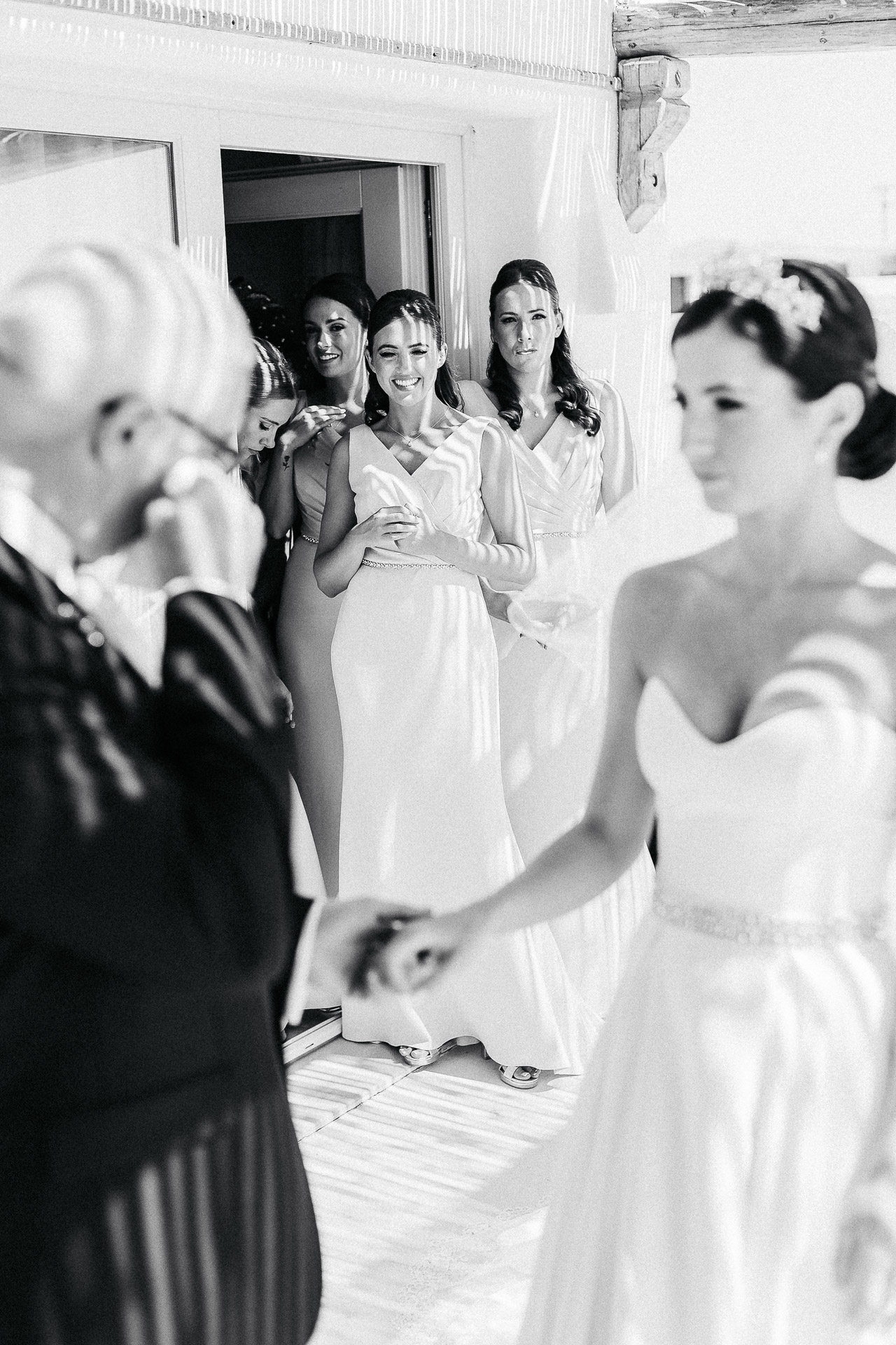 Santorini wedding photographer captures emotional moment between bride and father as bridesmaids look on