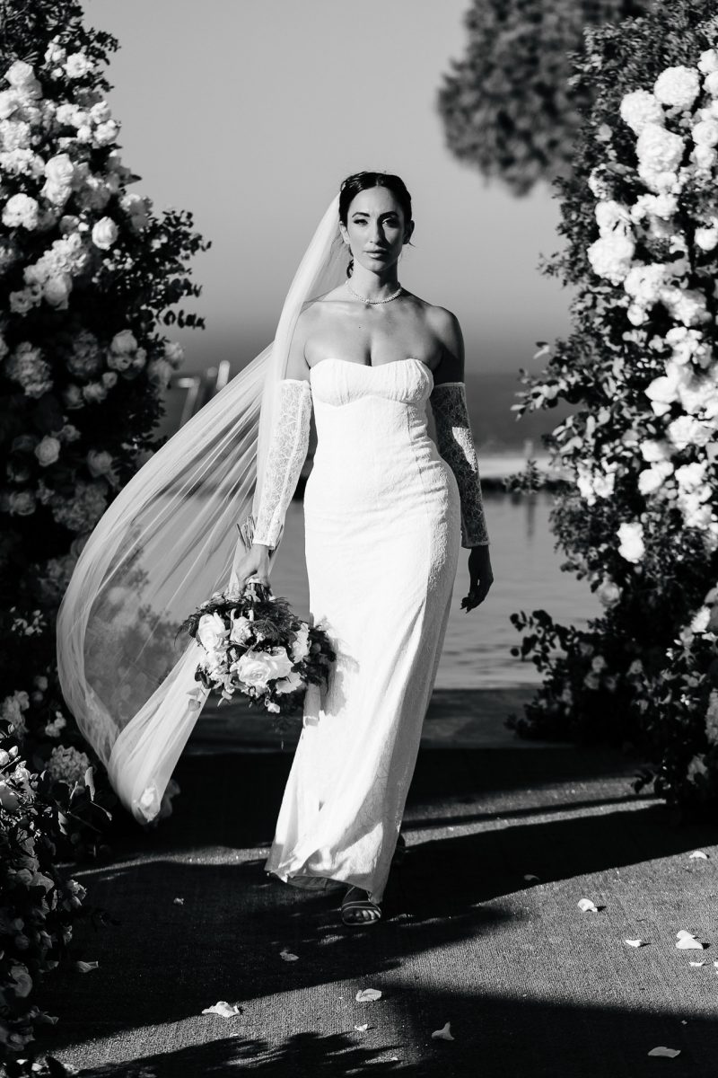Santorini wedding photographer captures elegant bride walking with bouquet