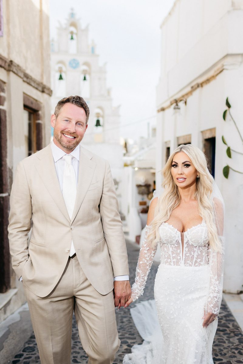 Santorini wedding photographer captures bride and groom walking in Fira.