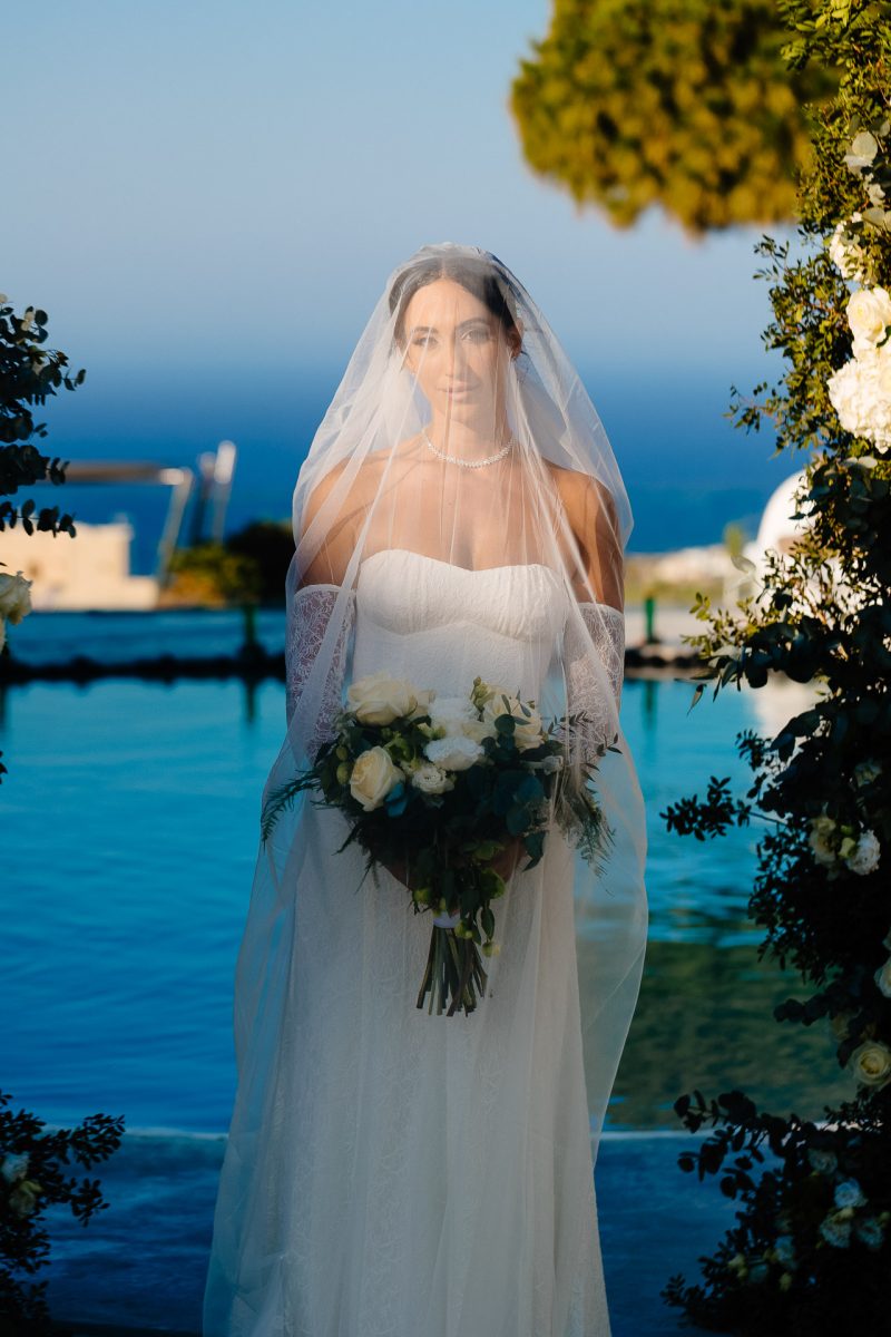 Bride under veil by pool in Santorini wedding photographer image