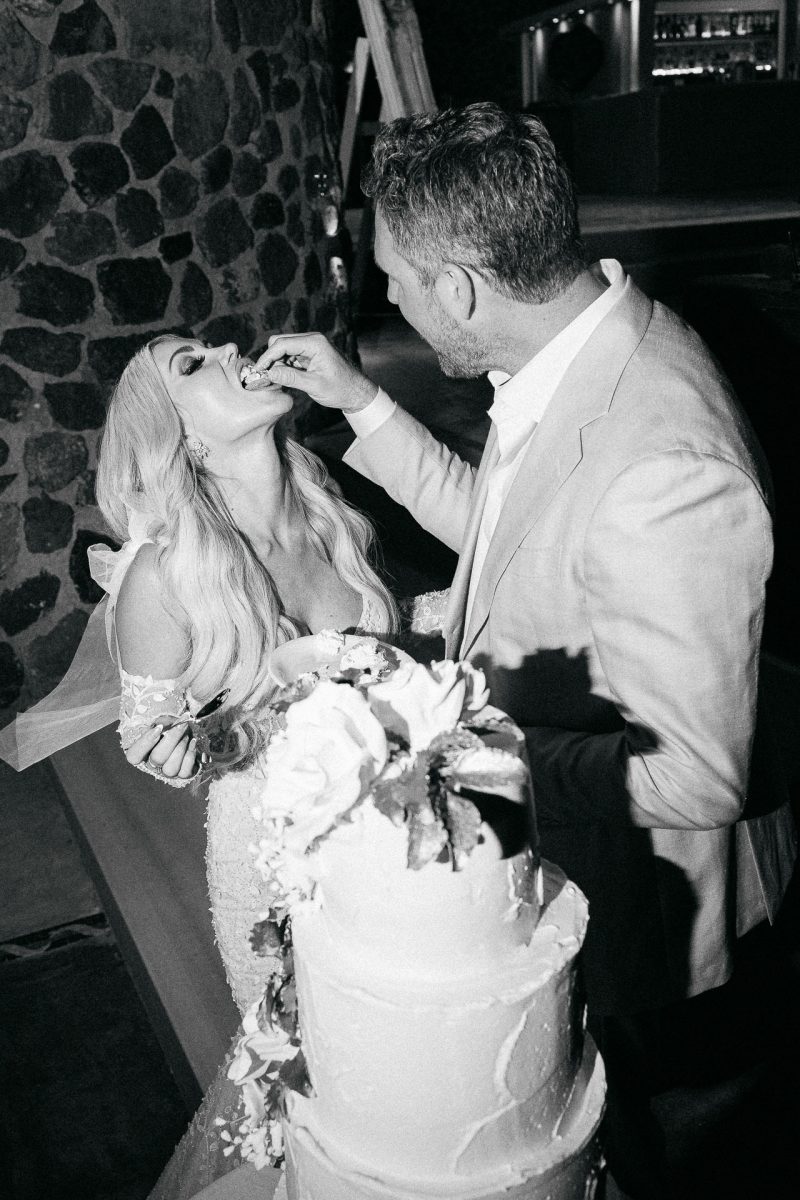 Santorini wedding photographer captures bride and groom sharing cake.