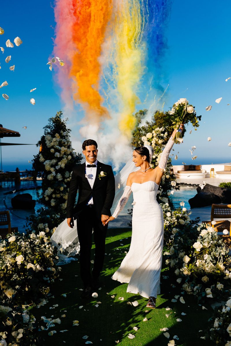 Santorini wedding photographer captures bride and groom celebrating with smoke and petals