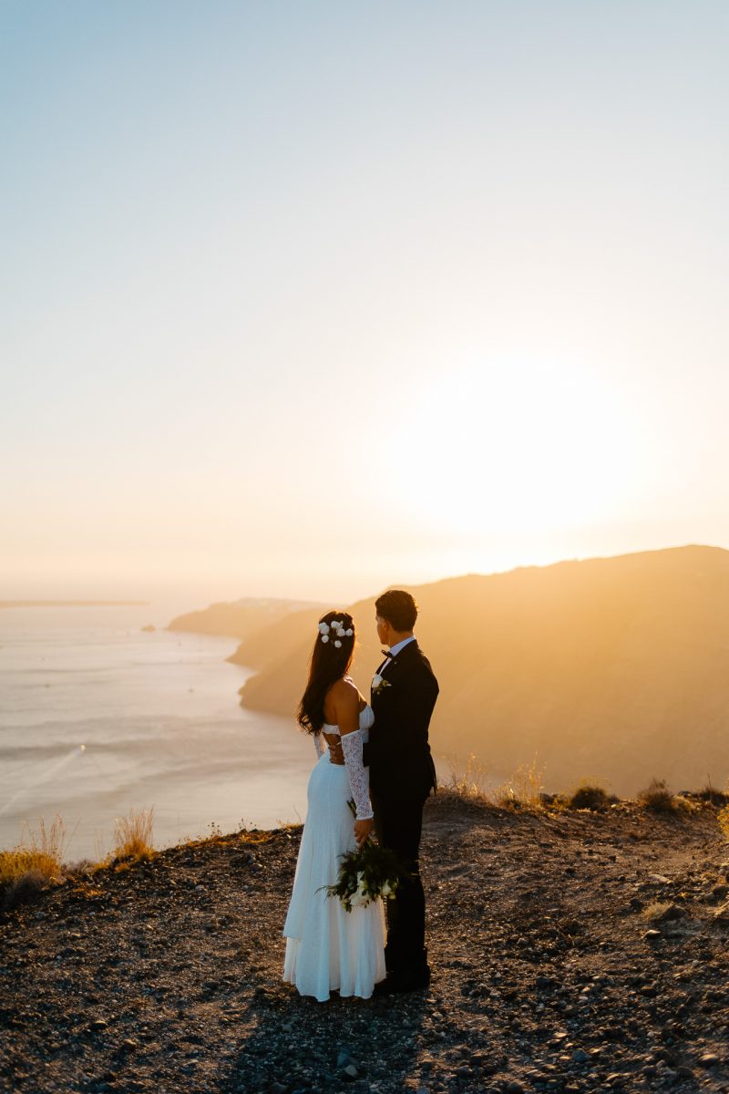 Santorini wedding photographer sunset cliffside couple embrace