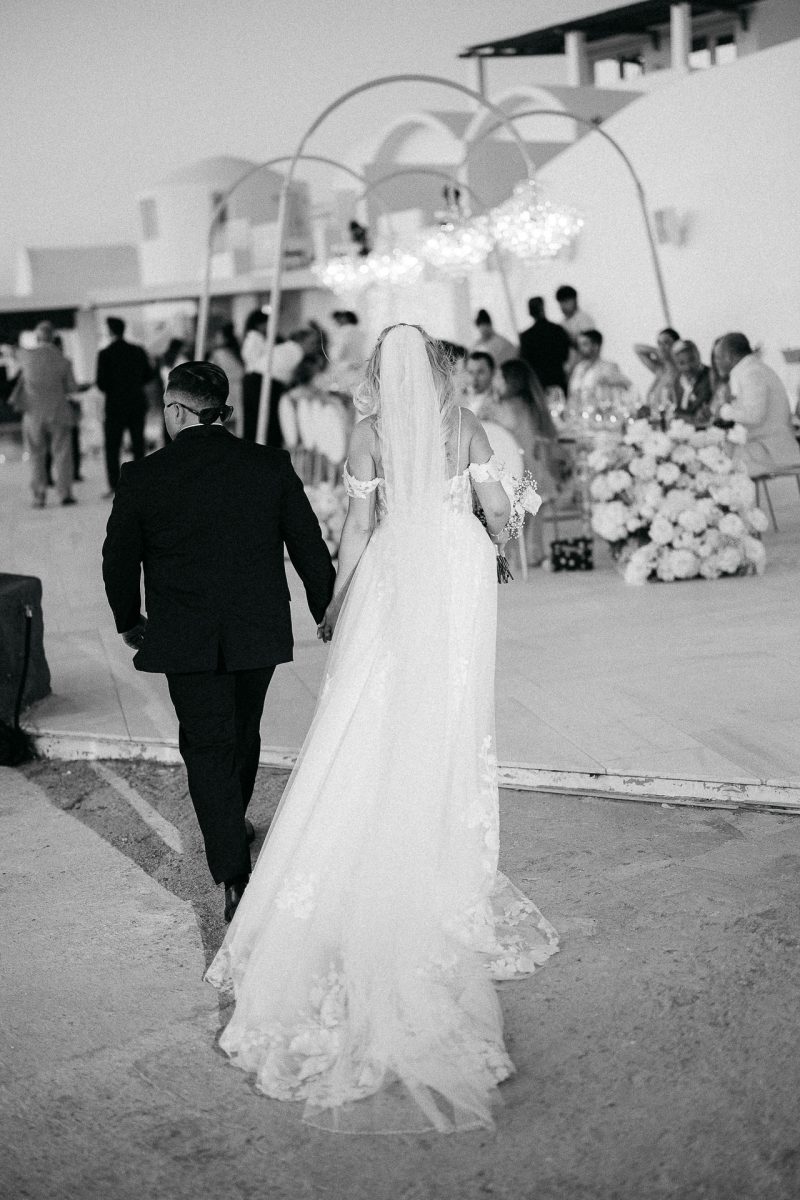 Bride and groom walking to wedding reception by Santorini wedding photographer
