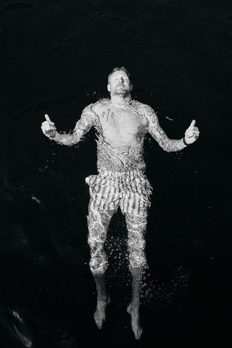 Groom floating in sea during Santorini wedding, by Santorini wedding photographer.