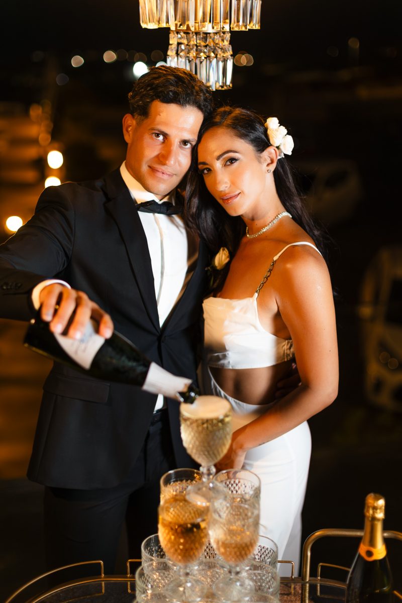 Santorini wedding photographer captures bride and groom champagne toast at night