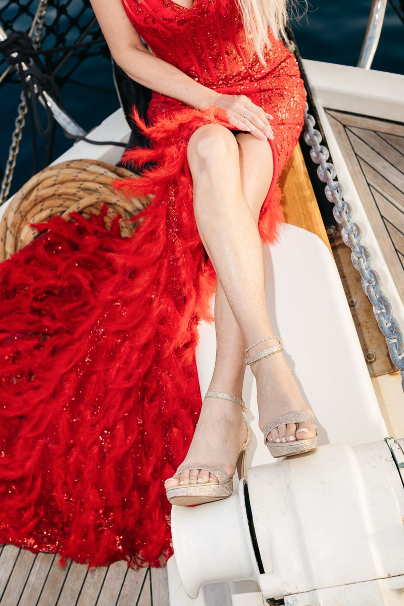 glamorous bridal look in red dress on boat by Santorini wedding photographer