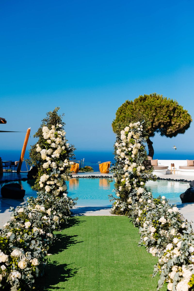 Santorini wedding ceremony setup with white florals and sea view