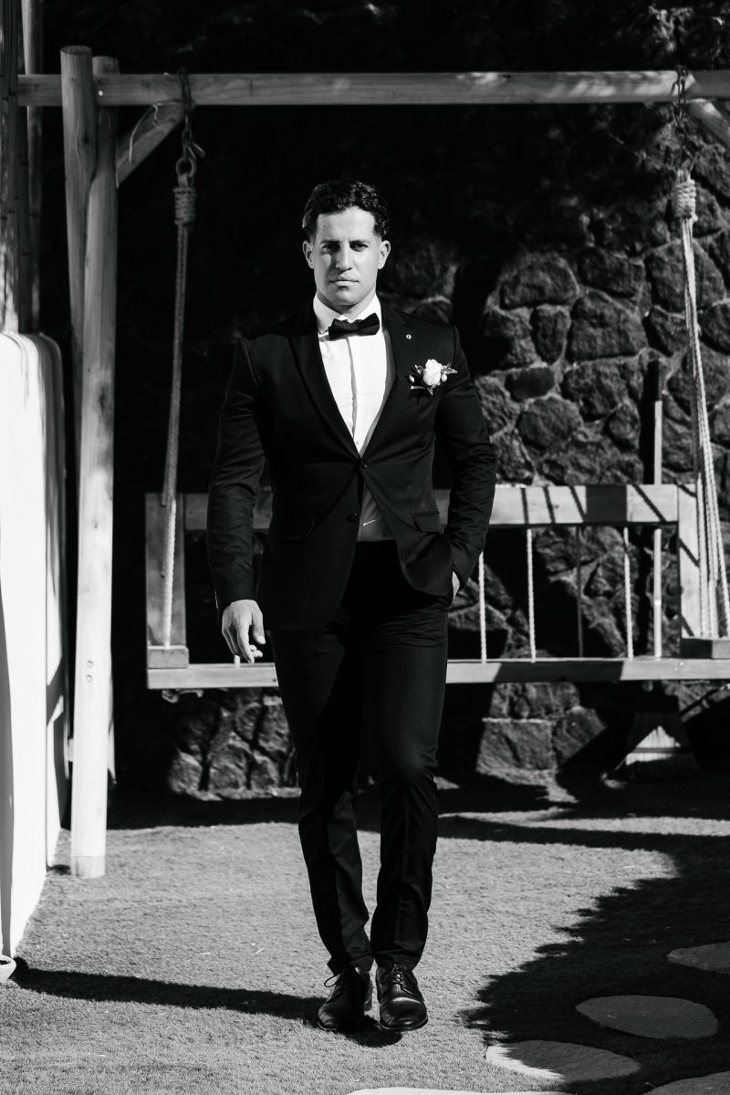 Confident groom walking in tuxedo, Santorini wedding photographer